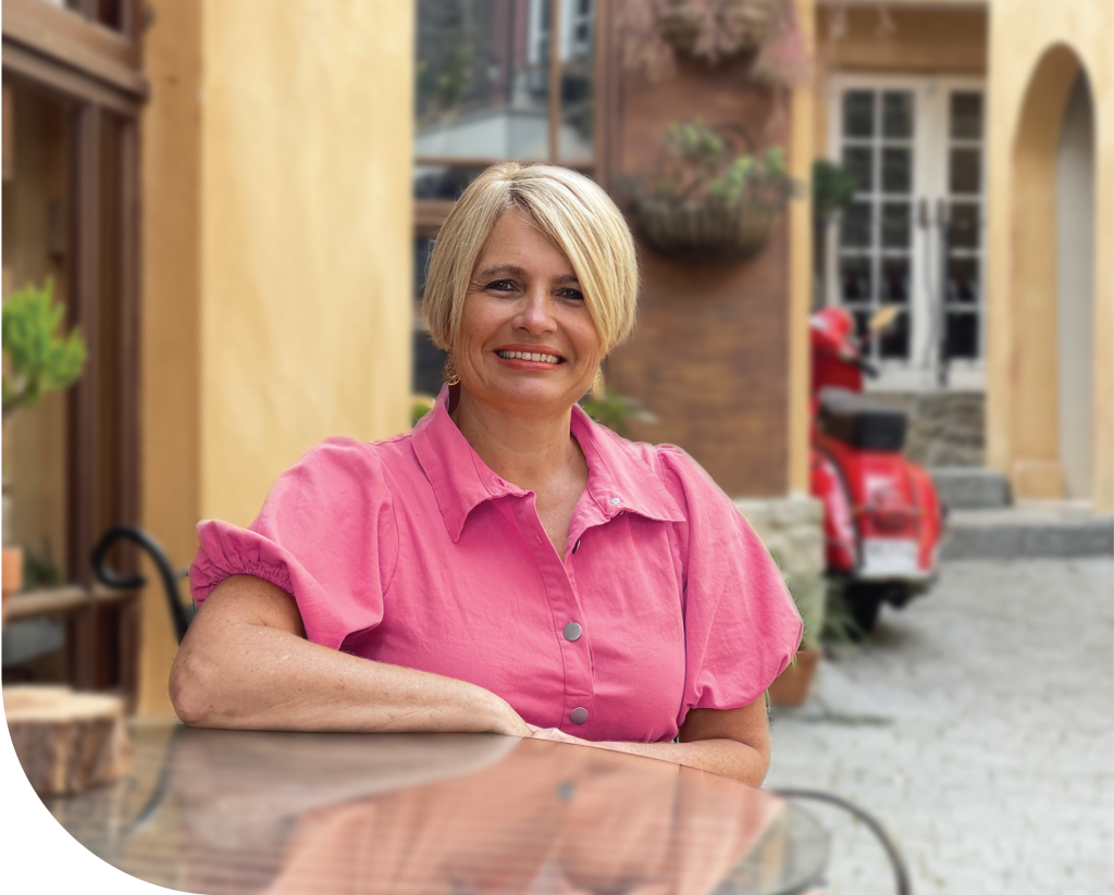 Jenny Vile sitting at a table wearing a pink dress